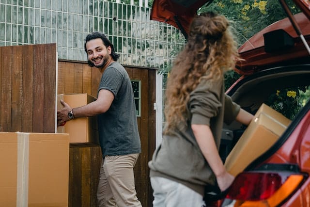 A couple carrying boxes from the car during relocation