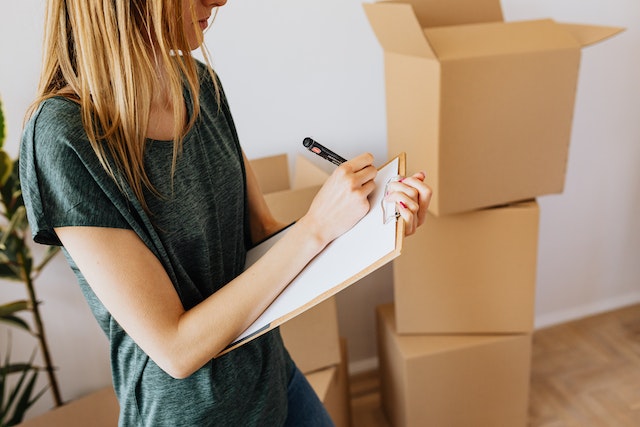A woman writing on the paper how to avoid a DIY move. 